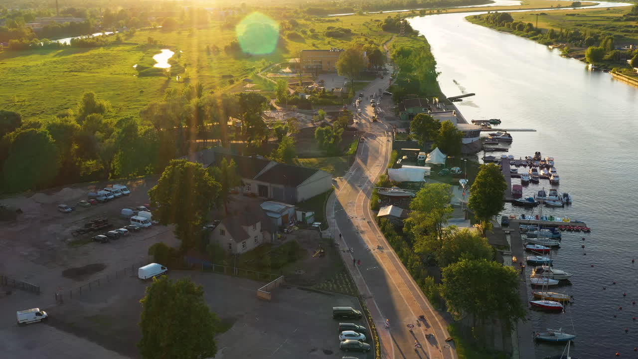 Serene riverside view of boats docked at the marina on the Driksa River, Jelgava during golden hour