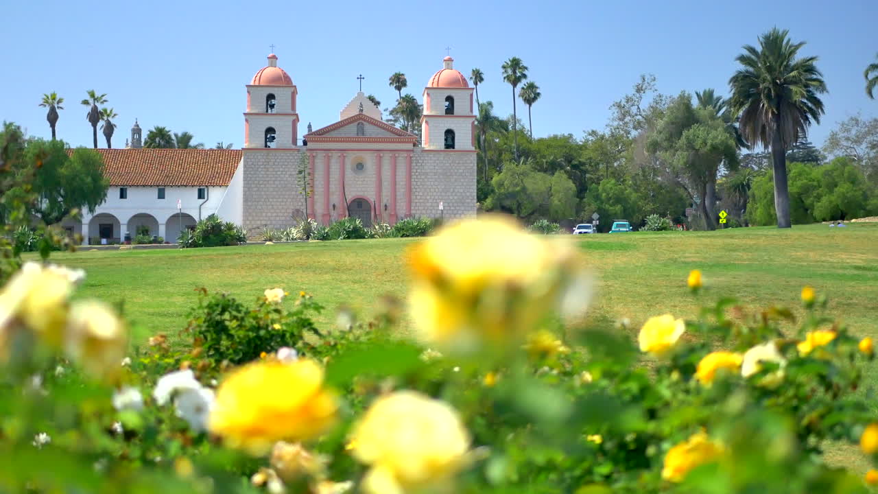 mirando hacia la misión de santa bárbara en un día soleado de verano con rosas amarillas en primer plano