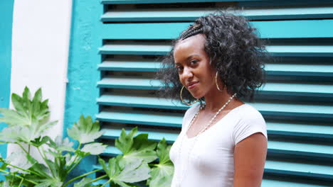 fashionable young black woman standing outdoors looks to camera, waist up