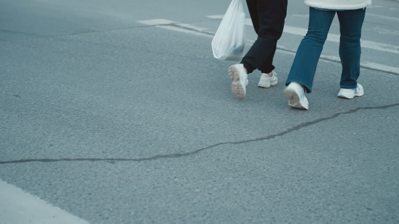 카메라가 하부 몸과 신발에 초점을 맞추는 도로를 가로질러 는 사람들의 발을 포착하는 가까운 시각