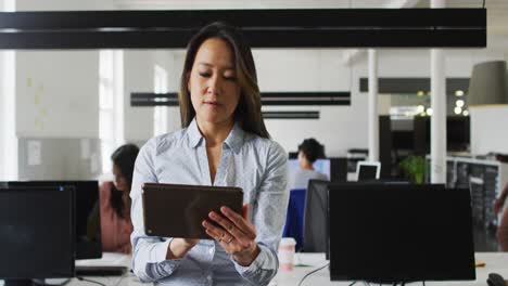 Focused-asian-businesswoman-working-on-tablet-in-office