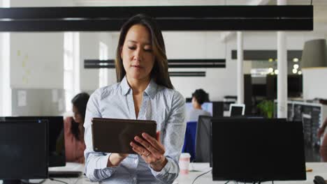 mujer de negocios asiática enfocada trabajando en una tableta en la oficina
