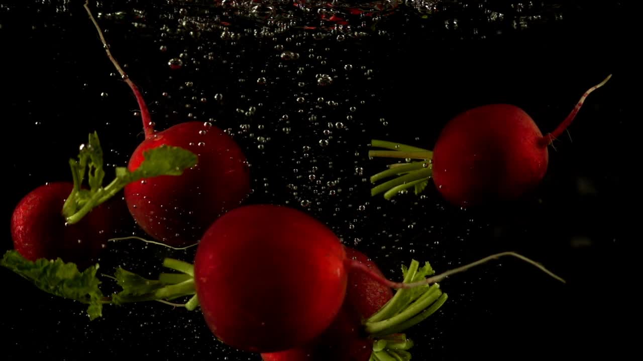 Falling of a radish in water. Slow motion. Black background