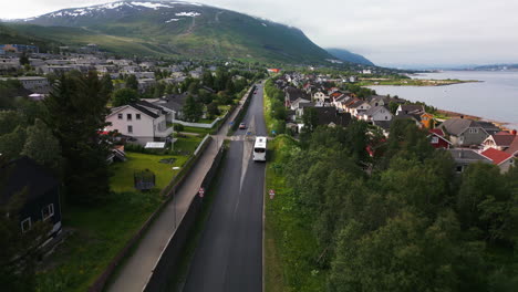 Aerial-tracking-of-bus-on-road-through-Tromso-neighborhood-with-wooden-houses