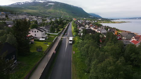 aerial tracking of bus on road through tromso neighborhood with wooden houses