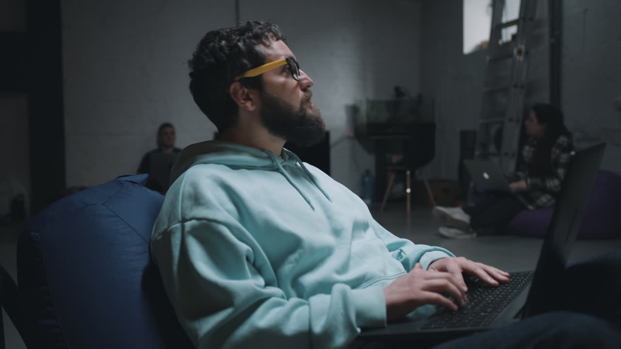 Man working on a laptop in a casual office setting.