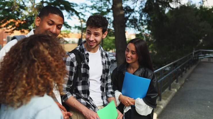 Felice gruppo eterogeneo di studenti che parlano e sorridono nel campus