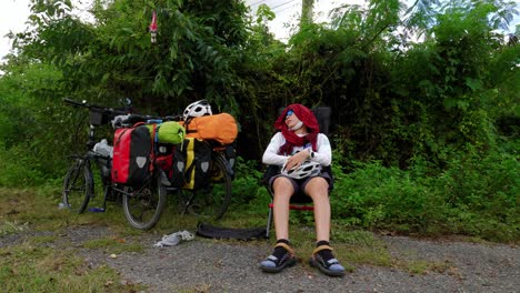 asian woman resting in foldout chair after bike ride through countryside, thailand