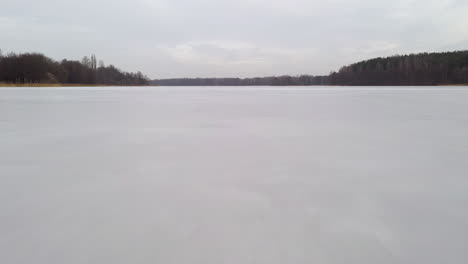 aerial: flying very low and close to the frozen lake surface on a cloudy day