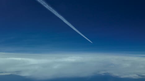 pov airplane wake flying very high in a clouded sky with a deep blue sky