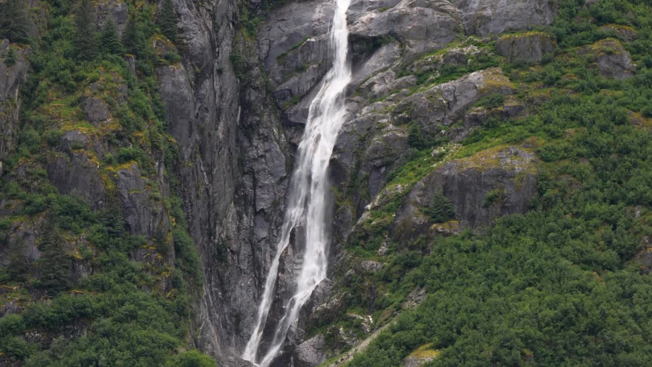 Picturesque waterfall along the granite steep wall of the mountain at Endicott Arm Fjord, Alaska.
