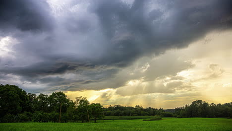 Filmischer-Zeitraffer-Von-Sich-Schnell-Bewegenden-Wolken-über-Einer-Graslandschaft-Mit-Bäumen-Und-Der-Sonne,-Die-An-Einem-Schönen-Tag-Durch-Die-Wolken-Scheint