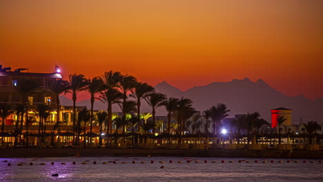 Tiro-De-Lapso-De-Tiempo-Que-Muestra-El-Paseo-Marítimo-De-Hurghada-Con-Palmeras-Y-Silueta-De-Montaña-Durante-El-Atardecer