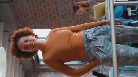 Vertical-Video-Portrait-Of-Smiling-Businesswoman-In-Office-With-Colleagues-Working-In-Background