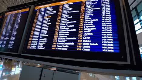 wide-angle video shot of an airport departure board displaying flight information