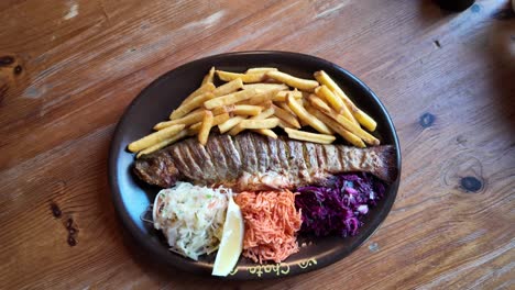 trucha fresca horneada con papas fritas en un plato marrón