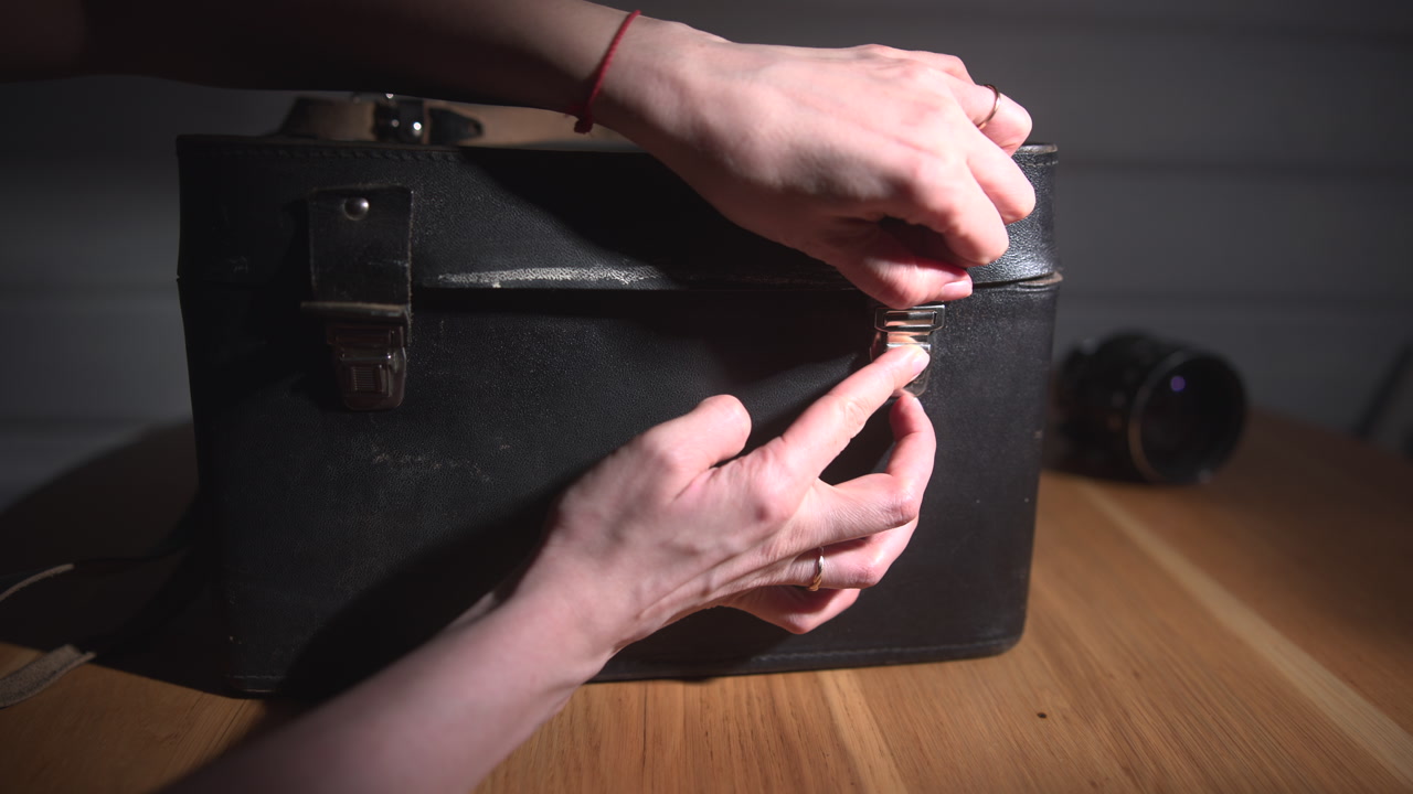 Closeup Hands Unlocking Worn Camera Case Latch, Careful Finger Motions, Slow Release Of Metal Clasp, Indoor . Media