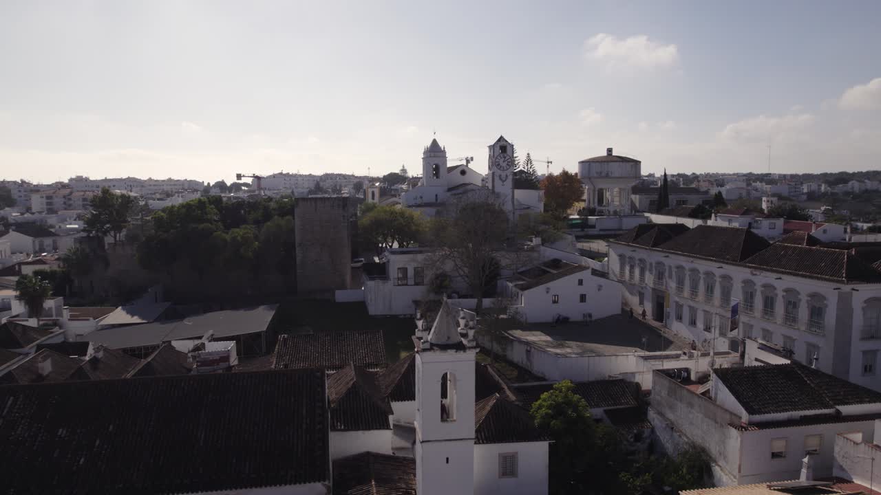 antena orbitando sobre el paisaje urbano de tavira, con la iglesia de santa maría en la distancia, día soleado