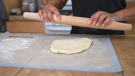 black woman using rolling pin on dough in home kitchen, slow motion close up