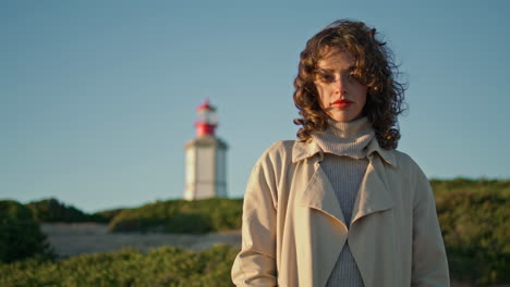 chica tranquila viendo la puesta de sol en el faro sola. mujer pensativa rizada mira la cámara