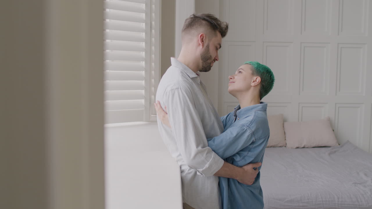 사랑하는 부부가 서로를 다정하게 바라보며 침실 창가에 서서 포옹했다