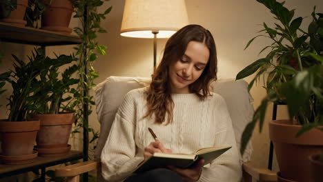 woman writing in journal amidst indoor plants