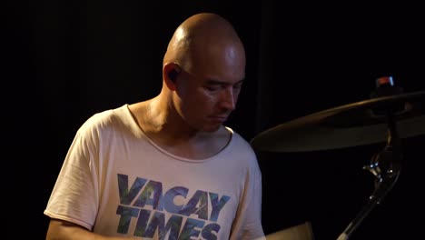 Close up of a drummer while he is playing his instrument and sweating a lot