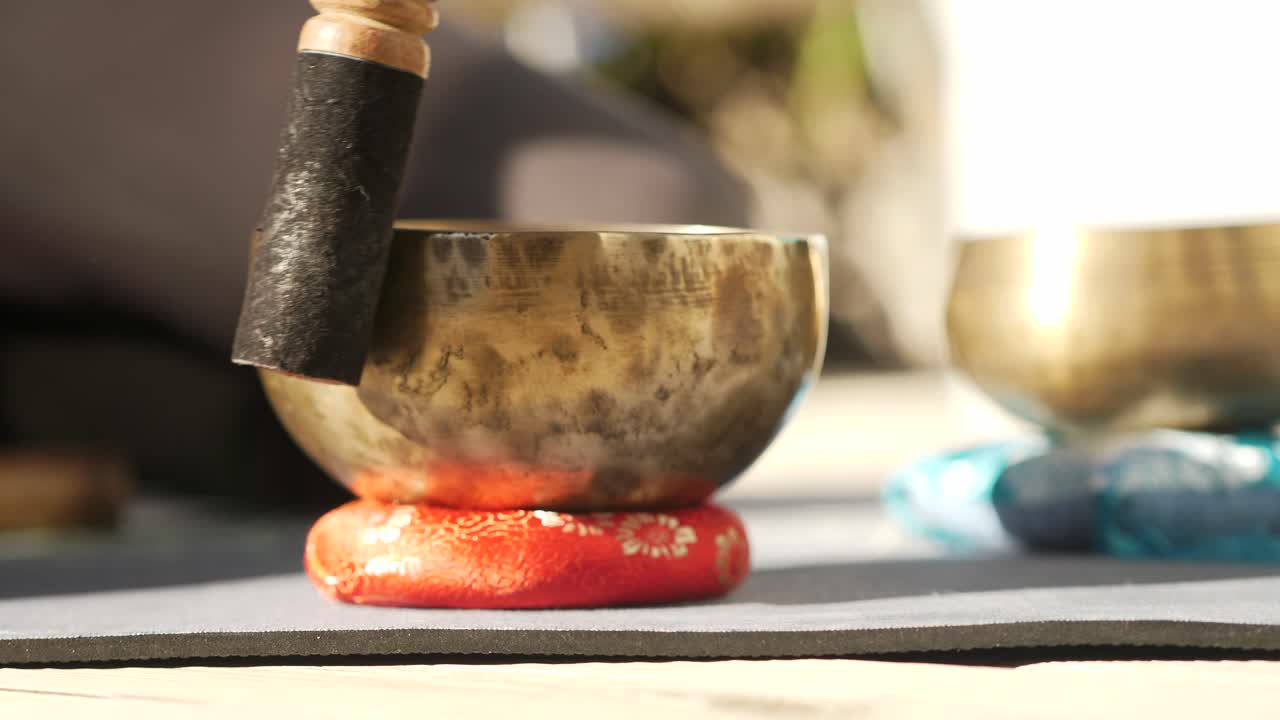 A singing bowl on a table is circled with a mallet to create relaxing sounds