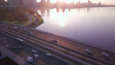 aerial view of a narrows bridge with busy morning commute, camera motion forward revealing perth cbd skyline at sunrise