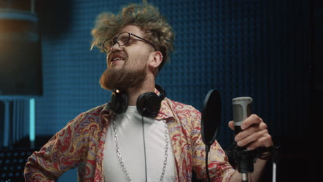 retrato del joven y apuesto cantante sonriendo alegremente a la cámara mientras estaba parado frente al micrófono en el estudio de sonido