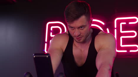 Man doing cardio in gym. Athletic man riding on bicycle at gym