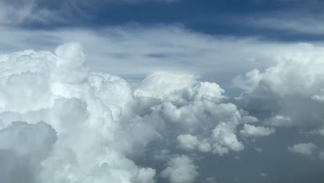 Aerial-view-from-a-jet-cockpit,-pilot-POV-while-flying-through-a-stormy-and-messy-sky-with-a-deep-blue-sky