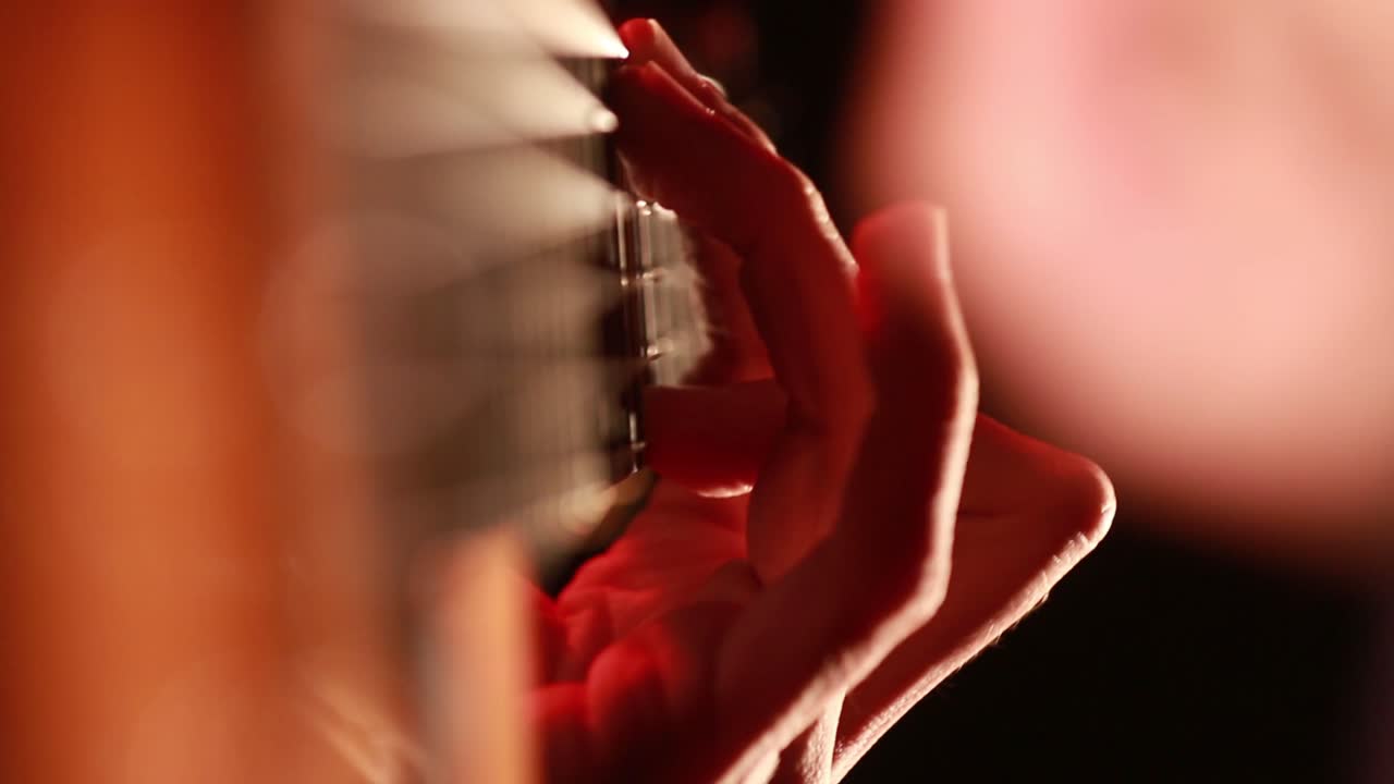 黒の暗い背景でクラシック ギターのクローズ アップ マクロを演奏するぼやけた手