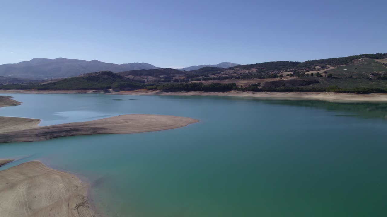 Lake with calm waters and the sky reflected in it. Mirror effect. Aerial view of a beautiful lake surrounded by mountains. Sky and clouds reflected in the lake waters. Granada. Spain