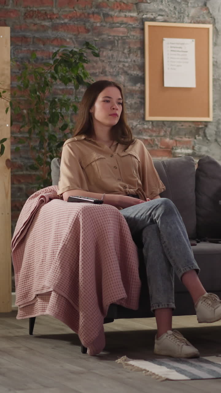 Man with glasses smokes vape sitting with tranquil young woman at football game broadcasting in apartment. Sports fans at awkward dating at home