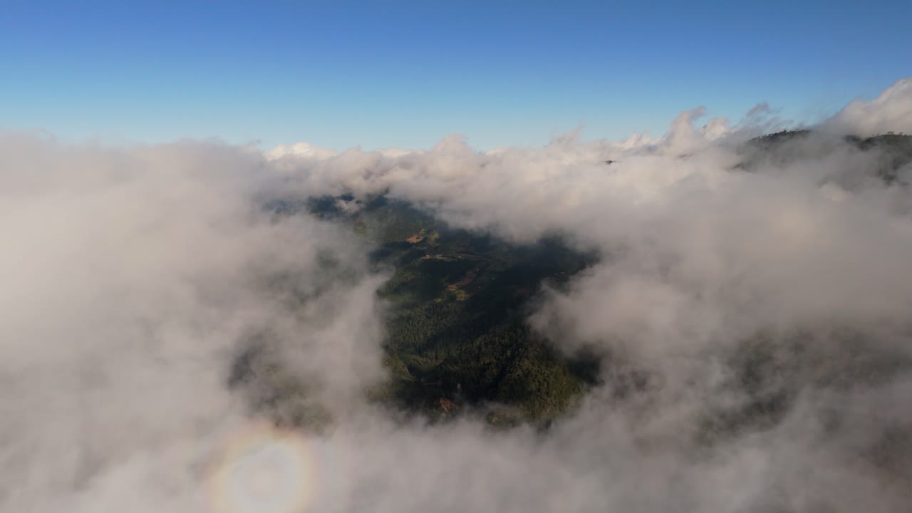 Aerial drone shot rising above dense clouds over Zacatlan, with a backward movement revealing forested mountains