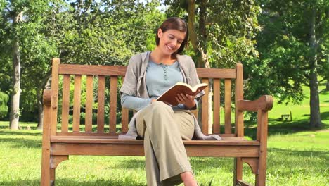 young woman reading a book on a public bench