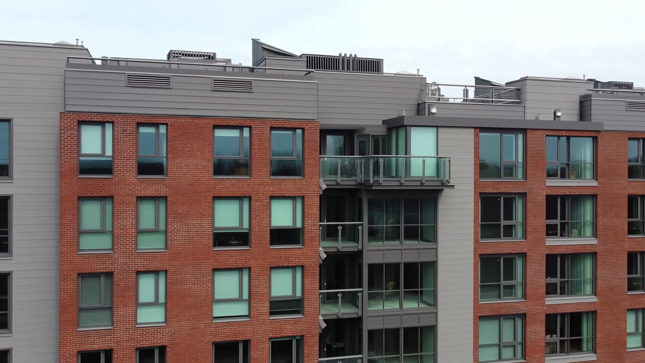 Aerial View Modern Brick Apartment Building Facade Showing Glass Balconies And Grid Windows Under Overcast