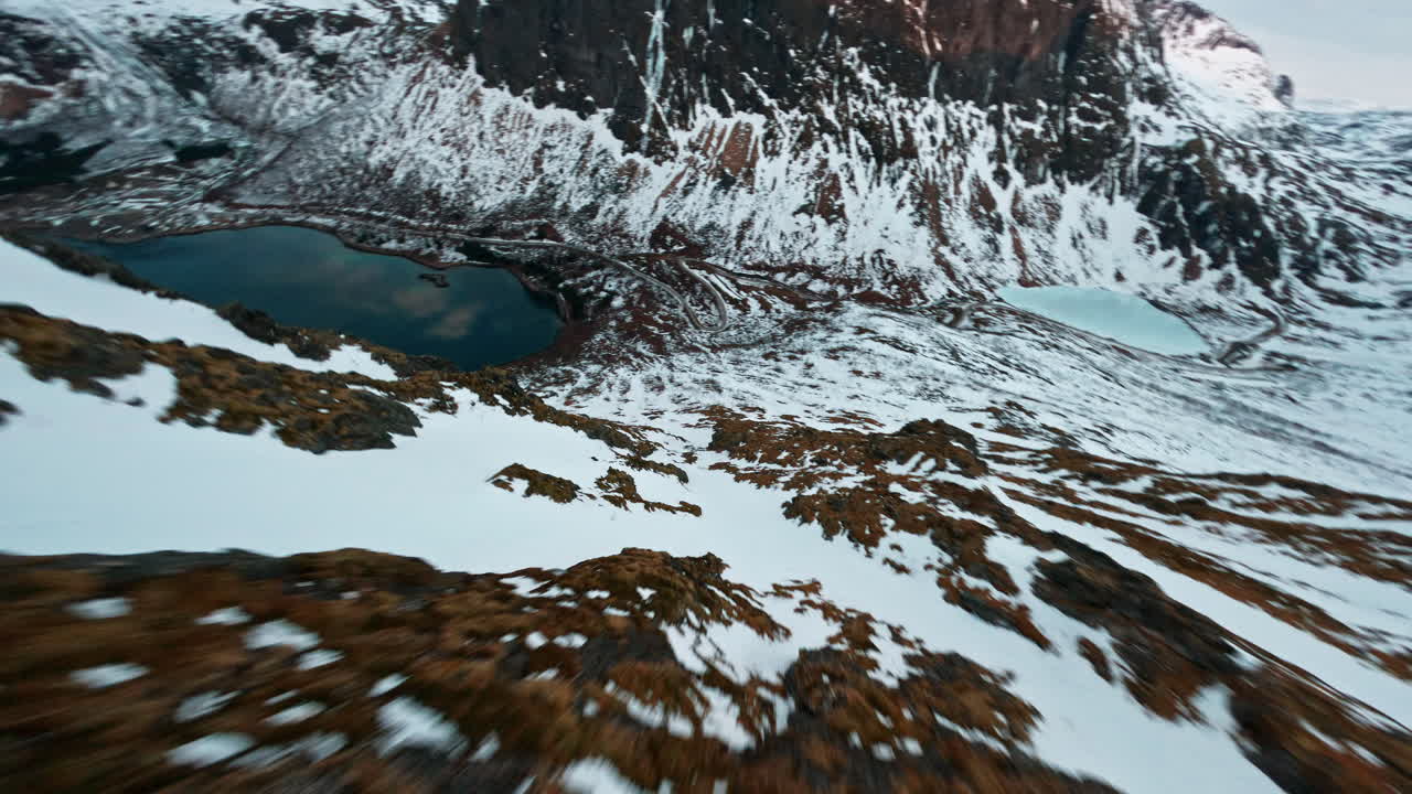 Snow-covered mountain slopes on Senja Island with lakes and rocky peaks