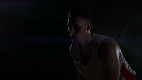 dribbling basketball player close-up in dark room in smoke close-up in slow motion