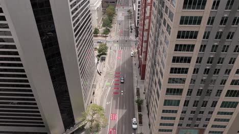 aerial top down of traffic on road in denver city, flying close to skyscrapers surroundings