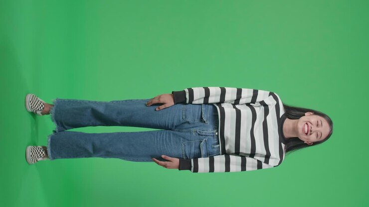 Full Body Of A Smiling Asian Woman Dabbing While Standing In Front Of Green Screen Background