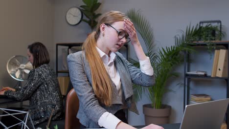 jefe de mujer joven aburrida haciendo un gesto de la palma de la cara mientras desarrolla un nuevo proyecto en una computadora portátil