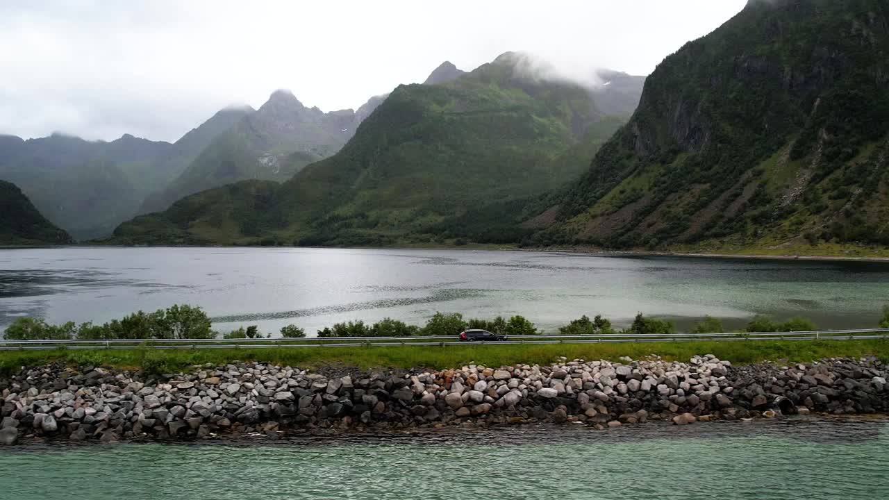 노르웨이 로포텐 에서 열대 물 과 산 을 둘러싸고 있는 도로 에서 운전 하는 자동차 의 공중 사진