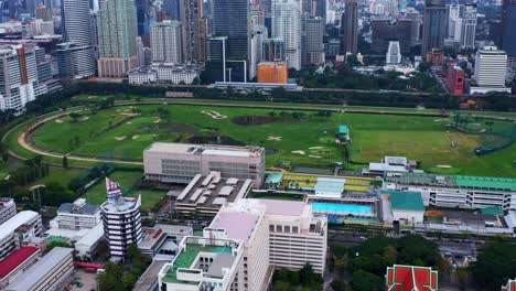 Vista-Aérea-Del-Campo-De-Prácticas-De-Golf-Rbsc-Con-Los-Edificios-Del-Centro-De-Bangkok-Al-Fondo---Bangkok,-Tailandia