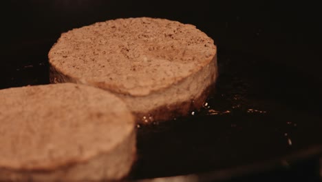 hamburguesas congeladas a base de plantas fritas en sartén con la cámara tirando del enfoque