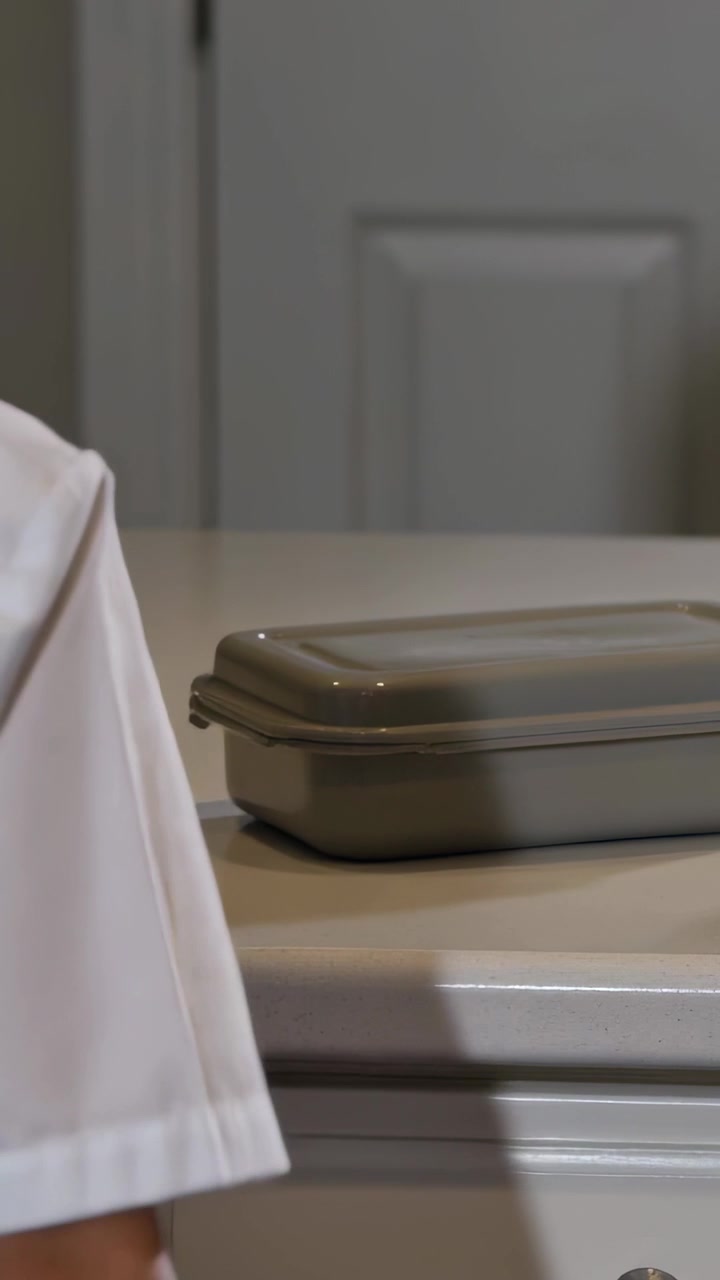 Vertical video: Reaching boy in uniform placing gray tin near shaker on kitchen counter, copy space