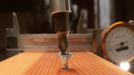 Close-up-is-an-electric-drill-the-screws-a-self-tapping-screw-into-a-wooden-bar.