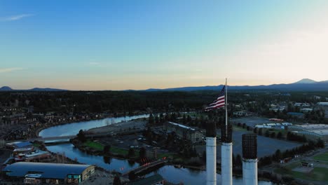 drone shot of the american flag waving over bend, oregon at sunset