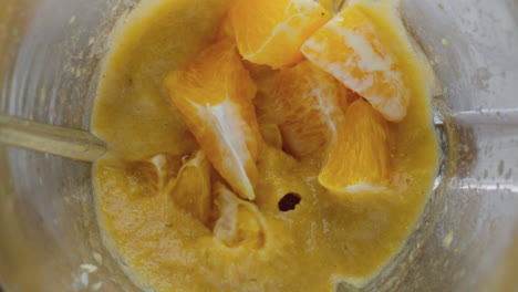 juicy orange pieces blending in mixer close up top view. cooking tasty dessert.